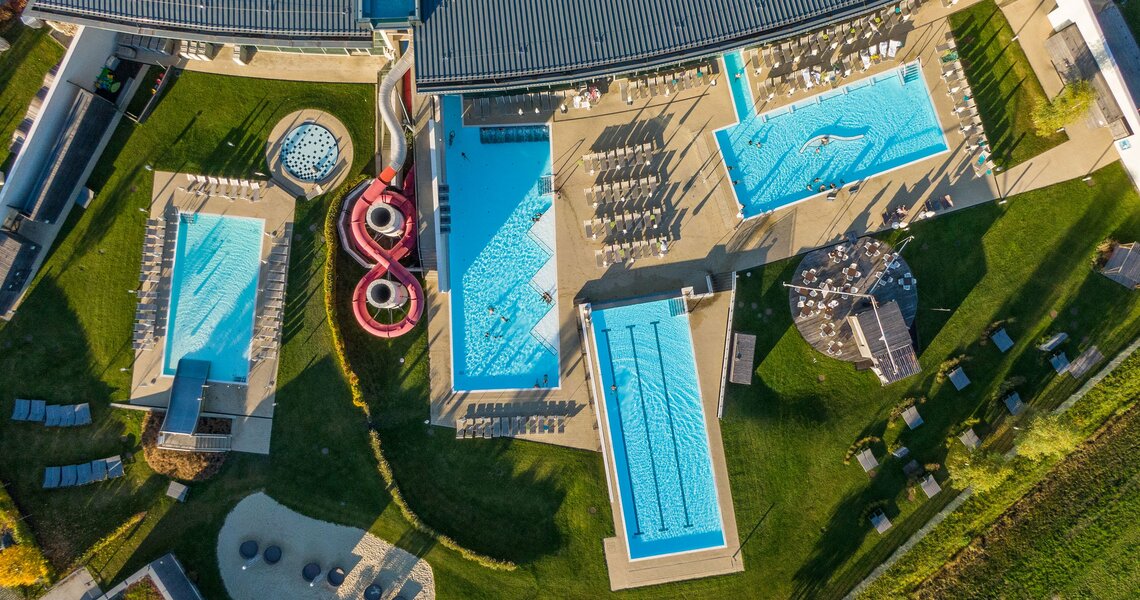 Luftaufnahme eines modernen Freibads mit mehreren Pools, Rutschen und Liegebereichen. | © Ferienregion Nationalpark Hohe Tauern