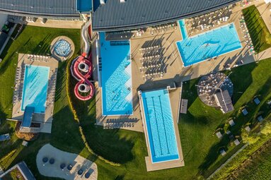 Luftaufnahme eines modernen Freibads mit mehreren Pools, Rutschen und Liegebereichen. | © Ferienregion Nationalpark Hohe Tauern
