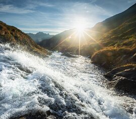 Fließender Bergbach im Sonnenlicht mit Blick auf Täler und Berge unter klarem Himmel Obersulzbachtal. | © Ferienregion Nationalpark Hohe Tauern - Daniel Breuer