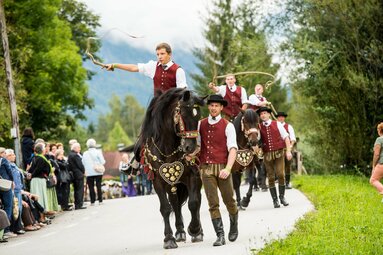 Traditioneller Festumzug mit geschmückten Pferden und Reitern in Tracht, begleitet von Zuschauern. | © SalzburgerLand Tourismus