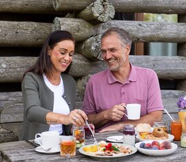 Mann und Frau frühstücken mit regionalen Spezialitäten draußen. | © Ferienregion Nationalpark Hohe Tauern - Carletto Photography