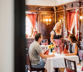 Kellnerin serviert Getränke im Restaurant mit Holzeinrichtung. | © SalzburgerLand Tourismus - Chris Perkles