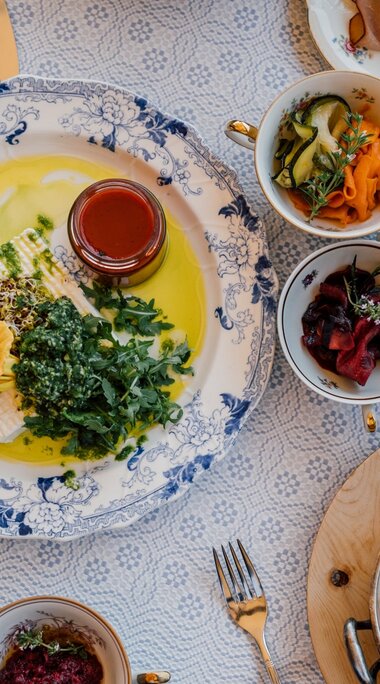 Bunte alpine Mahlzeit mit Käse, Spinatknödeln, eingelegtem Gemüse und Kräutern auf einem Tisch. | © SalzburgerLand Tourismus - Chris Perkles