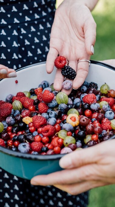 Zwei Frauen halten eine Schüssel voller Himbeeren, Blaubeeren und Johannisbeeren. | © SalzburgerLand Tourismus - Chris Perkles
