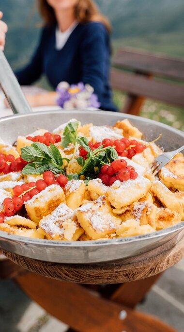 Kaiserschmarrn mit Beeren und Minze wird in einer Pfanne auf einer Almhütte serviert. | © SalzburgerLand Tourismus - Chris Perkles