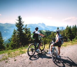Zwei Mountainbiker pausieren auf einem Schotterweg mit Bergpanorama. | © Ferienregion Nationalpark Hohe Tauern  - Daniel Kogler