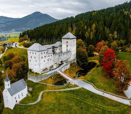 Burg in herbstlicher Landschaft mit Kirche, bunten Bäumen und bewaldeten Hügeln | © Zell am See-Kaprun Tourismus