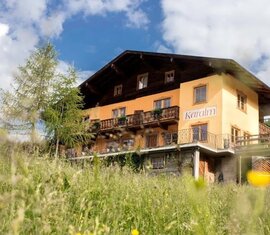 Karalm mit Balkon und Blumenschmuck auf einer Wiese unter blauem Himmel | © TVB Raurisertal