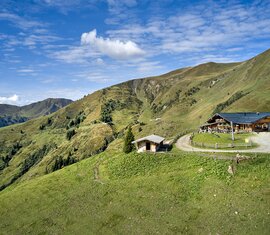 Almhütte in den Bergen mit Panoramablick auf sanfte Hügel und Wanderweg | © Tourismusverband Taxenbach