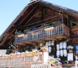 Traditionelle Almhütte mit Holzbalkon, Blumenschmuck und Milchkannen an der Fassade | © Hans Gruber, Tödlingalm
