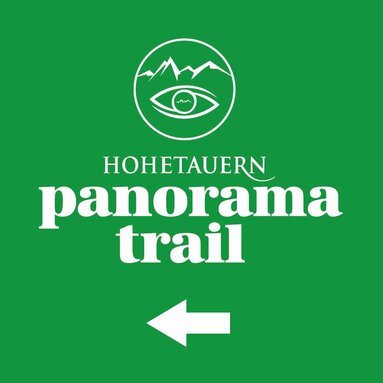 Green sign with "Hohe Tauern Panorama Trail" and an arrow pointing left.