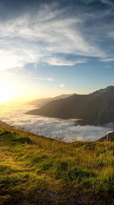 Summit cross on mountain meadow with sunrise and sea of clouds. | © Hohe Tauern National Park holiday region / Florian Kreidl-Glueck