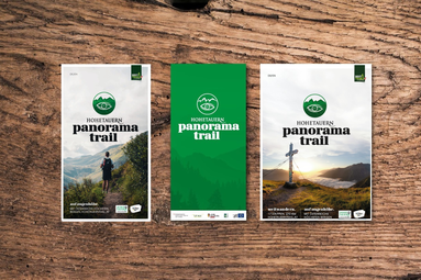 Three flyers of the Hohe Tauern Panorama Trail on wooden background featuring hiking and mountain motifs. | © Hohe Tauern National Park holiday region 