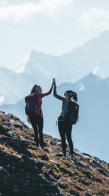 Zwei Frauen geben High Five beim Wandern im Gebirge. | © Ferienregion Nationalpark Hohe Tauern - Daniel Kogler