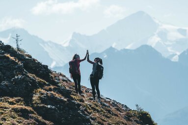 Zwei Frauen geben High Five beim Wandern im Gebirge. | © Ferienregion Nationalpark Hohe Tauern - Daniel Kogler