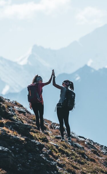 Zwei Frauen geben High Five beim Wandern im Gebirge. | © Ferienregion Nationalpark Hohe Tauern - Daniel Kogler