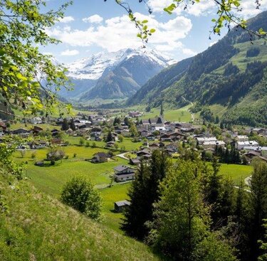 Malerisches Tal mit Dorf, grünen Wiesen und schneebedeckten Bergen im Hintergrund. | © Tourismusverband Rauris - Lukas Pilz