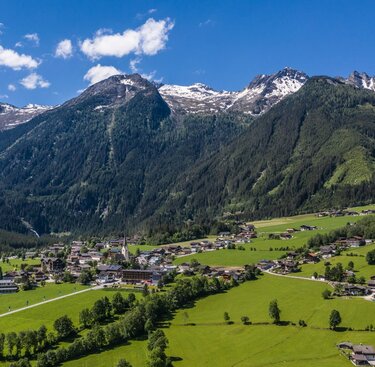 Malerisches Dorf mit grünen Wiesen und hohen Bergen unter klarem, blauem Himmel. | © Tourismusverband Krimml