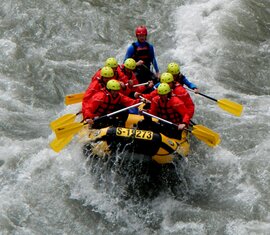 Rafting-Gruppe auf einem Fluss in einem Schlauchboot mit gelben Paddeln. | © FROST Rafting & Canyoning Tours