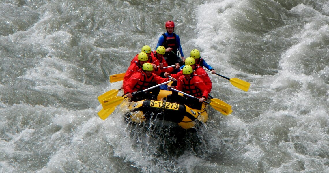 Rafting-Gruppe auf einem Fluss in einem Schlauchboot mit gelben Paddeln. | © FROST Rafting & Canyoning Tours