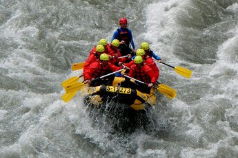 Rafting-Gruppe auf einem Fluss in einem Schlauchboot mit gelben Paddeln. | © FROST Rafting & Canyoning Tours