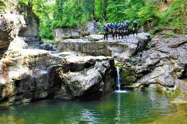 Gruppe von Personen in Neoprenanzügen bei einer Canyoning-Tour an einer felsigen Schlucht. | © FROST Rafting & Canyoning Tours