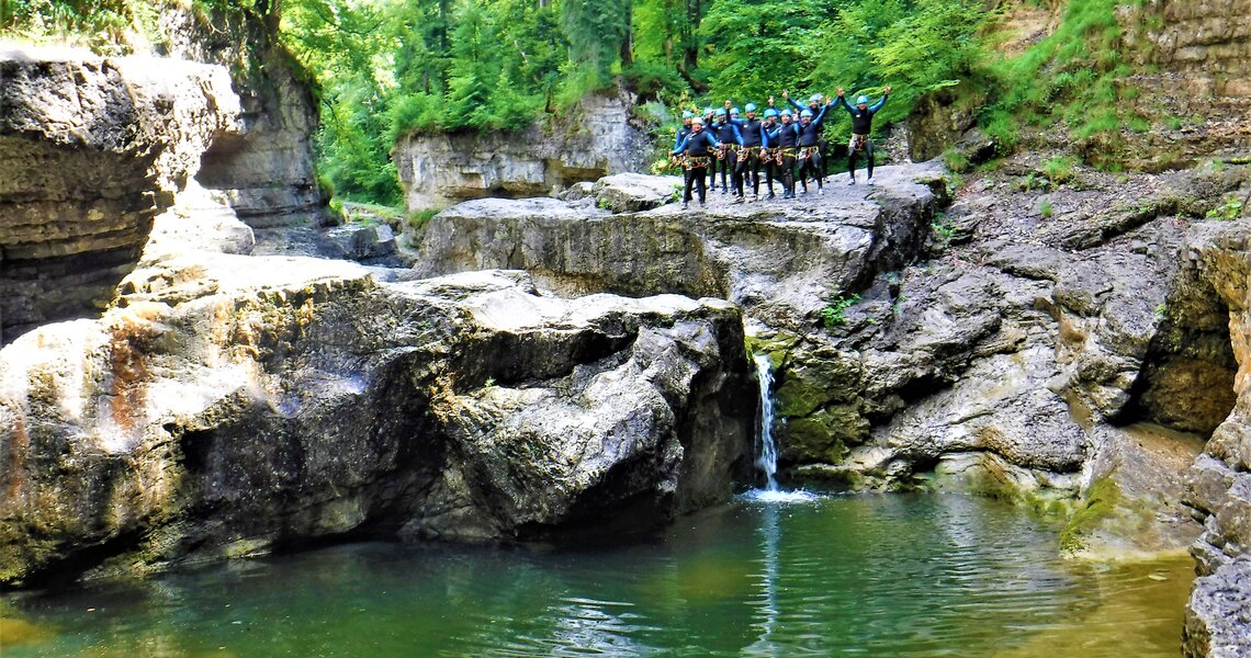 Gruppe von Personen in Neoprenanzügen bei einer Canyoning-Tour an einer felsigen Schlucht. | © FROST Rafting & Canyoning Tours