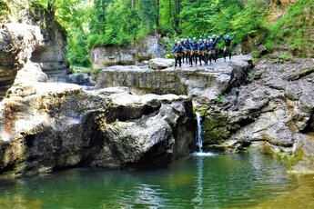 Gruppe von Personen in Neoprenanzügen bei einer Canyoning-Tour an einer felsigen Schlucht. | © FROST Rafting & Canyoning Tours