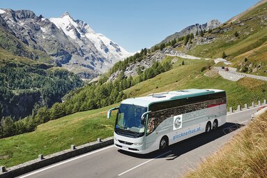 An excursion bus drives along the Großglockner High Alpine Road with views of glaciers and peaks. | © Vorderegger Travel - Andrea Stifter Touristik GmbH