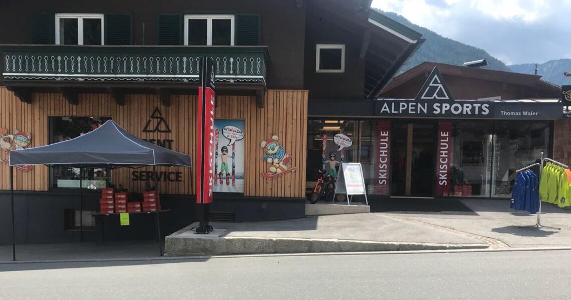 Alpen Sports Shop mit Skischule und Servicebereich vor alpiner Kulisse. | © Alpen Sports