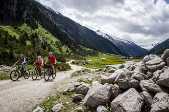 Gruppe von Radfahrern auf einem Bergpfad mit Alpenpanorama im Hintergrund. | © Intersport Pirchner