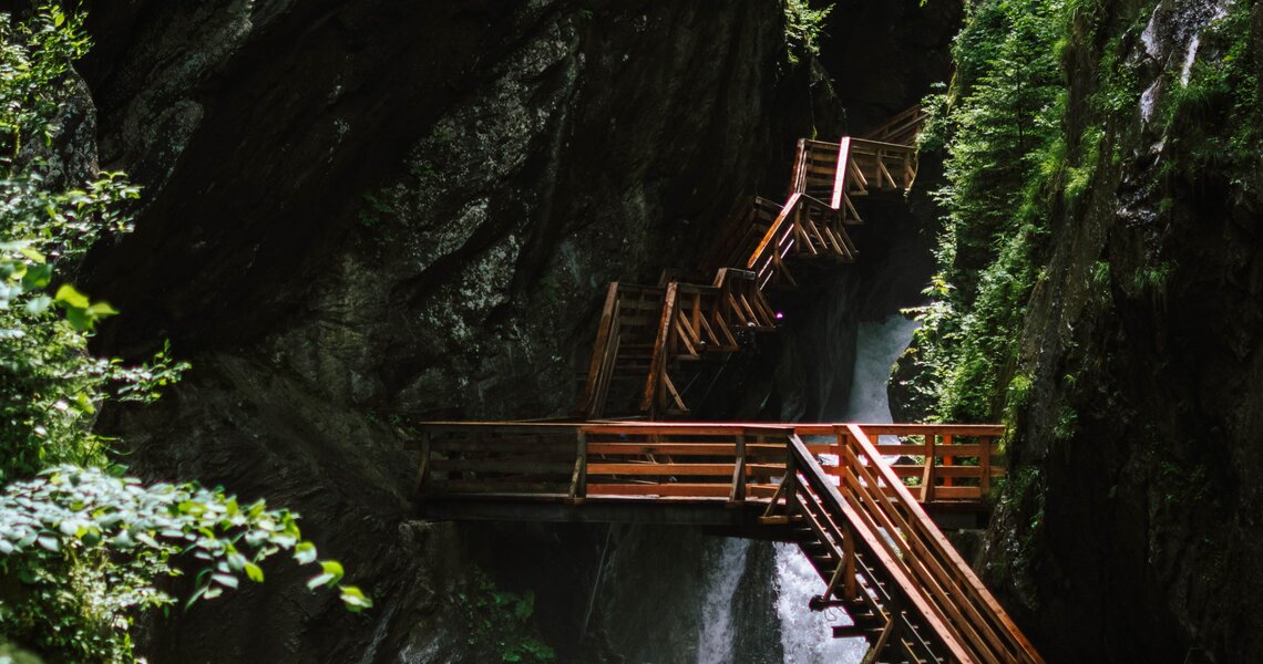 Holzstege und Treppen in der Sigmund-Thun-Klamm mit Wasserfall zwischen Felswänden. | © Sigmund Thun Klamm Kaprun