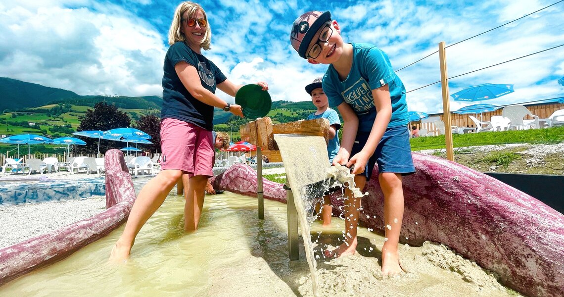 Kinder und Erwachsene spielen im Edelsteinpark Niedernsill mit Wasser und Sand. | ©  Edith Danzer