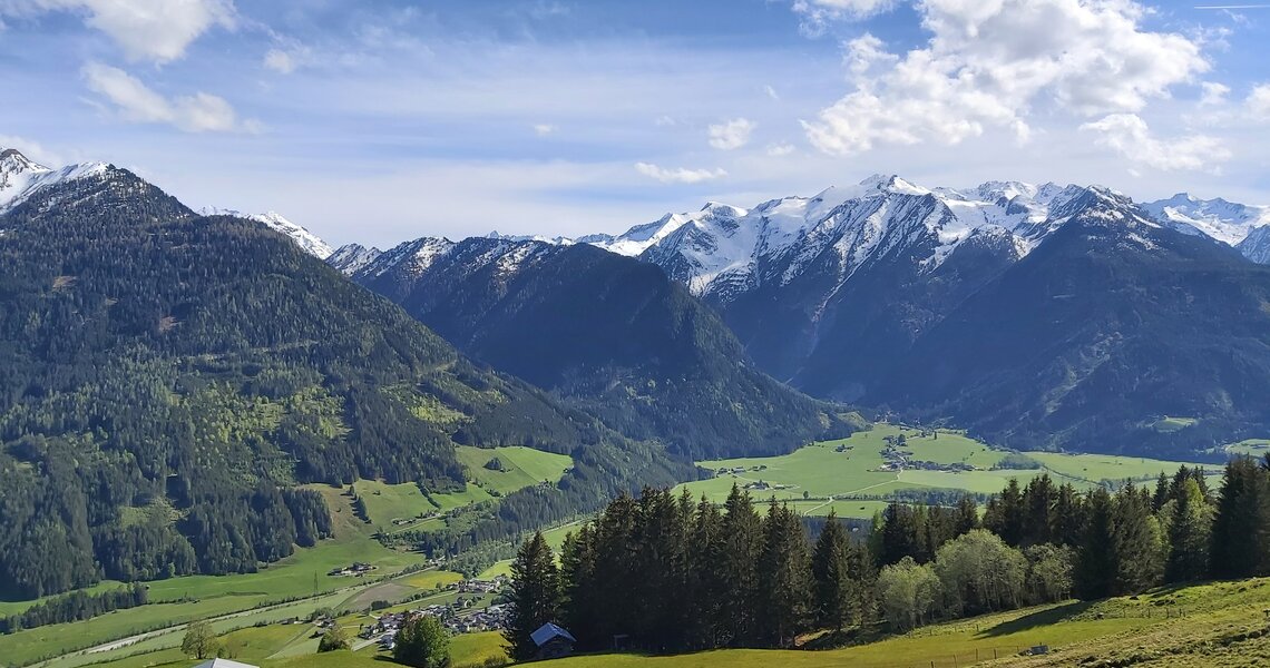 Panoramablick über ein grünes Tal auf bewaldete Berghänge und schneebedeckte Gipfel der Hohen Tauern. | © Bogensport Vorderegger
