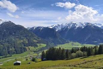 Panoramablick über ein grünes Tal auf bewaldete Berghänge und schneebedeckte Gipfel der Hohen Tauern. | © Bogensport Vorderegger