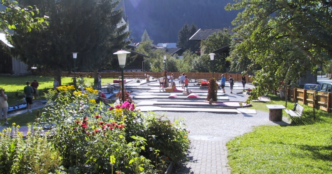 Schöne Minigolfanlage mit Blumen und Spazierweg in einer Berglandschaft. | © Minigolf Rauris