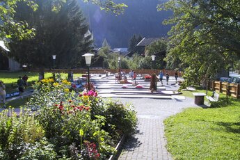 Schöne Minigolfanlage mit Blumen und Spazierweg in einer Berglandschaft. | © Minigolf Rauris
