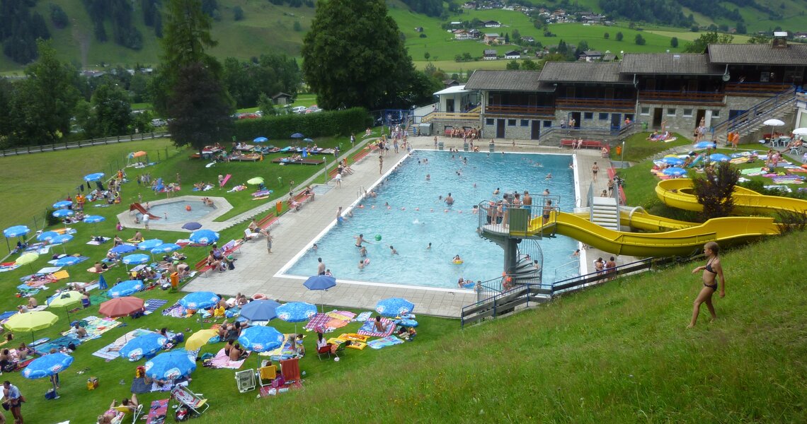 Schwimmbad mit Rutsche und grünem Bergpanorama im Sonnblickbad Rauris. | © Sonnblickbad Rauris