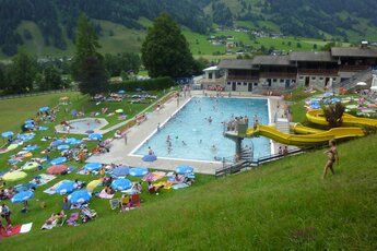 Schwimmbad mit Rutsche und grünem Bergpanorama im Sonnblickbad Rauris. | © Sonnblickbad Rauris