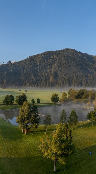 Panoramablick auf eine Freizeitanlage mit See, Sportfeldern und Bergen im Hintergrund. | © Freizeitanlage Hollersbach