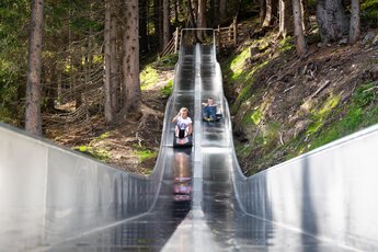 Kinder rutschen auf Edelstahlrutsche im Wald. | © Wildkogel-Arena Neukirchen & Bramberg