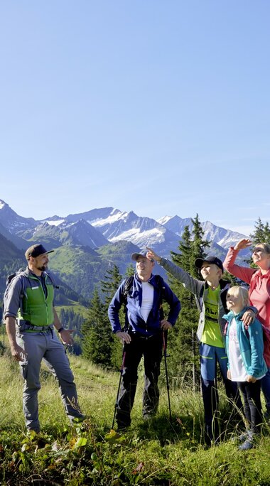 Eine Familie mit einem Ranger bewundert die Berglandschaft bei sonnigem Wetter im Nationalpark Hohe Tauern. | ©  Ferienregion Nationalpark Hohe Tauern - Michael Huber 