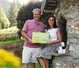 Mann und Frau mit Nationalpark SommerCard vor Steinhütte. | © Ferienregion Nationalpark Hohe Tauern - Carletto Photography