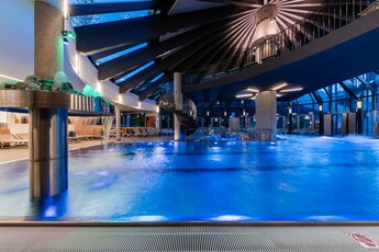 Innenansicht des beleuchteten Kristallbads Wald mit Pool und Liegen. | © © Kristallbad Wald Königsleiten GmbH