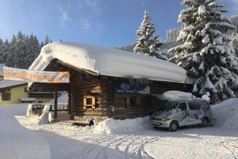 Skischule in Holzhaus mit tief verschneitem Dach. | © (c) Stefans Skischule