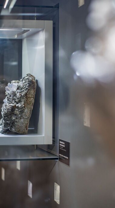 Mineral in einer beleuchteten Glasvitrine mit Spiegelungen im Museum. | ©  zangl.ultd-Franz Neumayr-Leo 