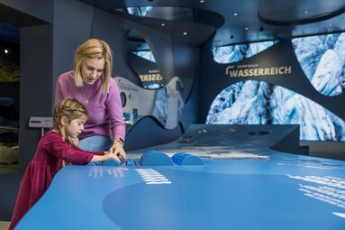 Mutter und Tochter erkunden eine interaktive Ausstellung zum Thema Wasser. | ©  zangl.ultd-Franz Neumayr-Leo 