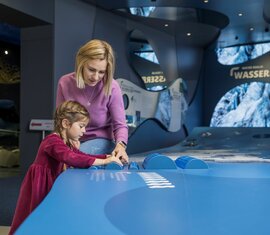 Mutter und Tochter erkunden eine interaktive Ausstellung zum Thema Wasser. | ©  zangl.ultd-Franz Neumayr-Leo 