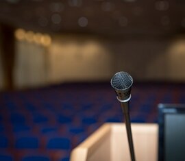 Mikrofon auf einem Rednerpult in einem leeren Konferenzraum mit unscharfen Sitzreihen | © Pixabay
