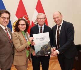 Vier Personen präsentieren ein Dokument mit dem Titel "Strategie 2030" vor Flaggen im Hintergrund. | © Pressefoto Franz Neumayr 